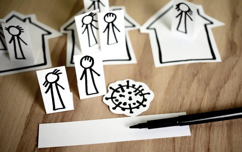 Picture of paper people inside paper houses, with a virus outside.